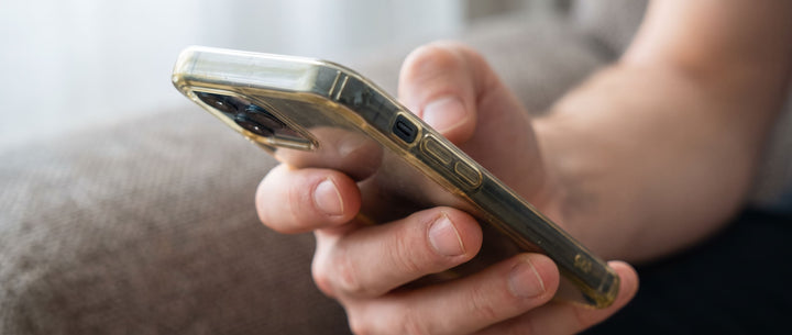 Close-up of a person holding a smartphone with a slightly yellowed clear case.